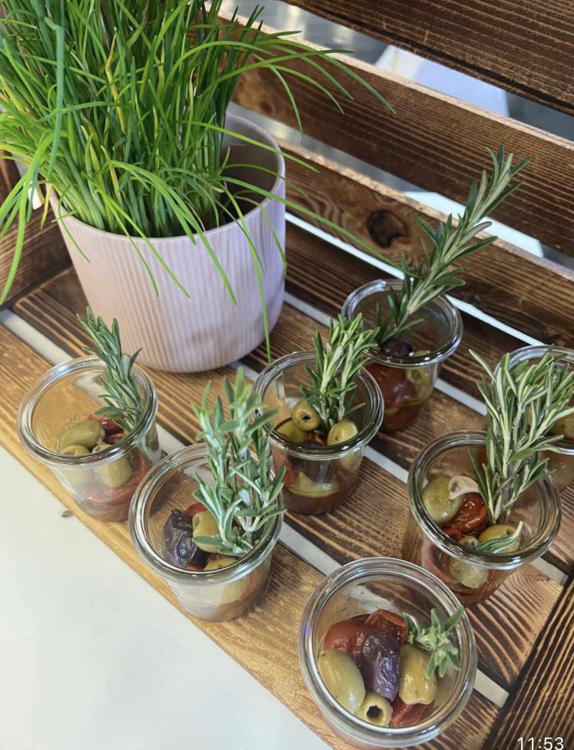 Antipasti-Gläschen mit Oliven, Tomaten und Rosmarin auf Holz-Display